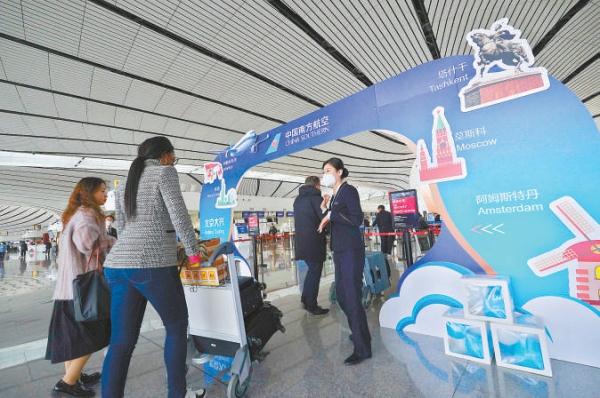 3月26日，在大兴国际机场，搭乘南方航空国际航班的旅客在工作人员引导下前往柜台办理业务。