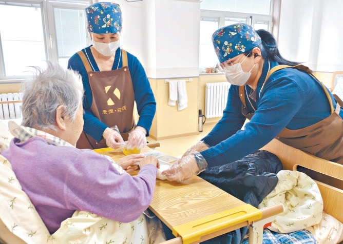 養老護理員和體驗工作的本報記者(右)給老人送餐。 養老護理員和體驗工作的本報記者(右)給老人送餐。