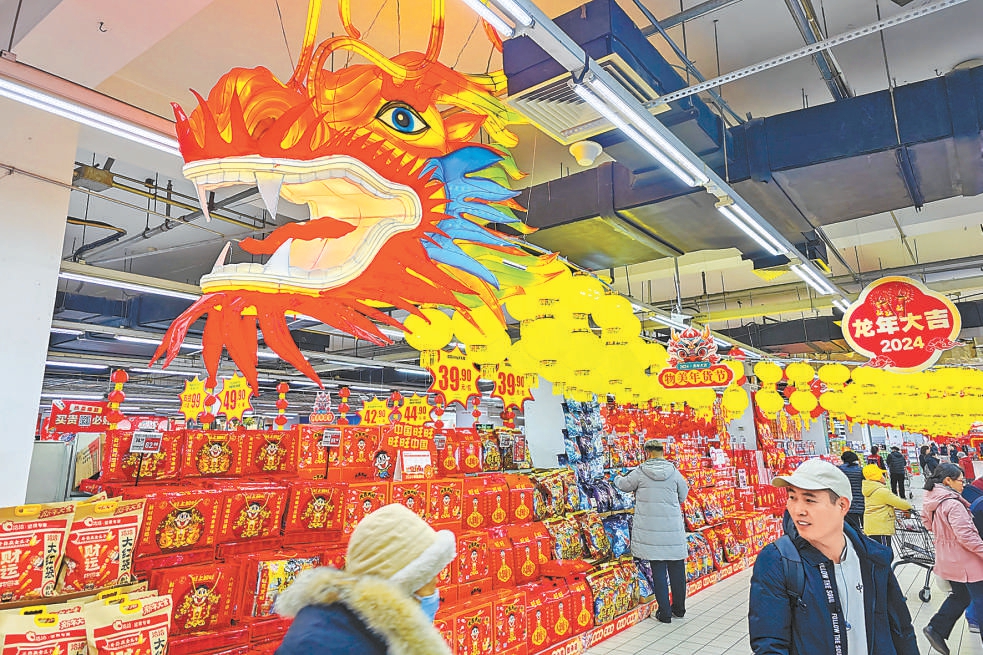 北京各大商超節日氛圍漸濃，在物美超市玉蜓橋店，新春節慶商品擺滿貨架，喜慶紅火的龍形挂飾裝點賣場。
