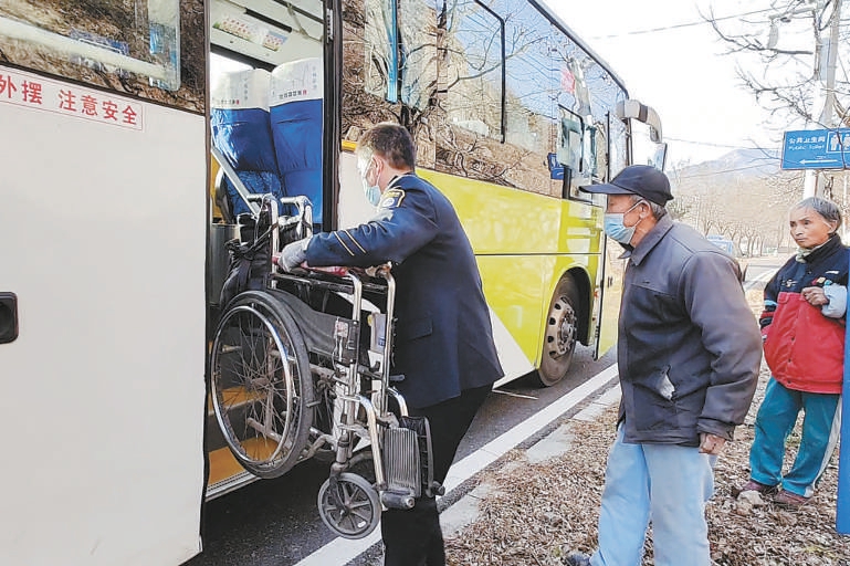 驾驶员常景生背残疾乘客上车后，将轮椅搬上车。