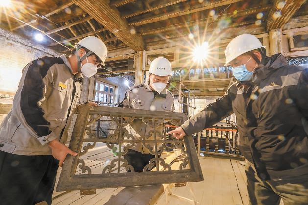 在東城區西曉市街同興和木器店舊址修繕現場，京誠集團老工匠劉京生（右）向年輕學員傳授技藝