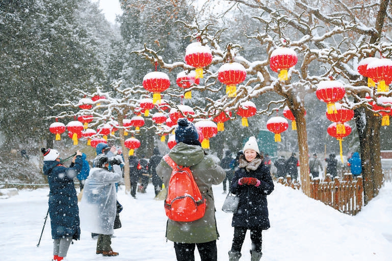 2022年2月13日，市民在景山公园欣赏雪景，在皑皑白雪的映衬下，一只只红灯笼化身“雪容融”。（安旭东 摄）