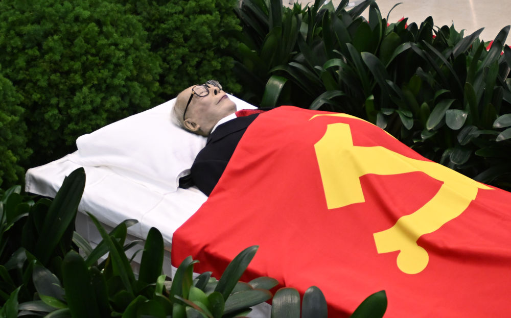 12月5日，江泽民同志的遗体安卧在鲜花翠柏丛中，身上覆盖着鲜红的中国共产党党旗。