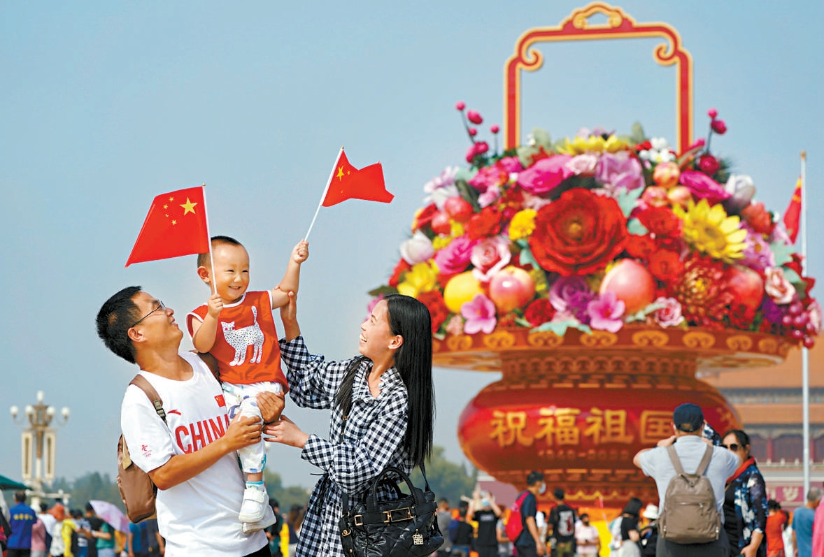 国庆节前夕，天安门广场上游人如织，一家三口在“祝福祖国”巨型花果篮前打卡留念。