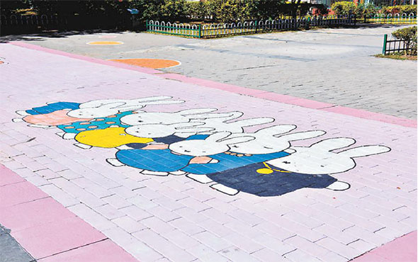 小广场的地面和井盖上手绘有卡通图案，成为孩子们的乐园。