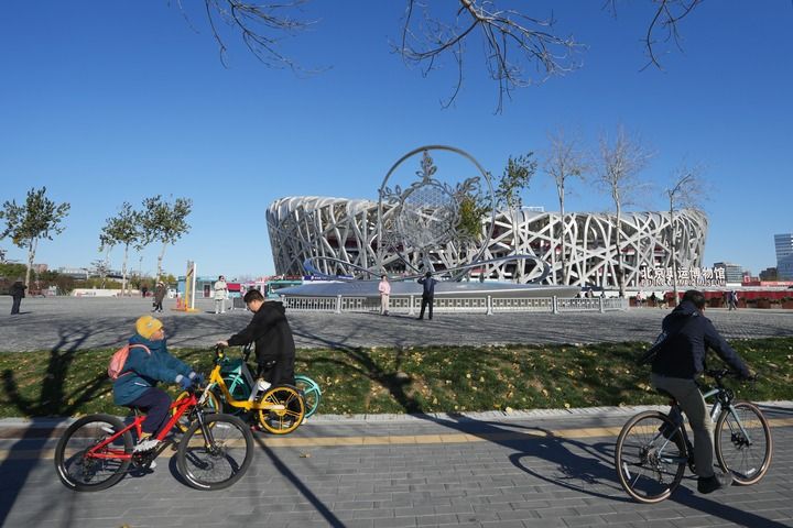 在北京奥林匹克公园，市民游客骑行在2022北京冬奥会主火炬前（11月17日摄）。
