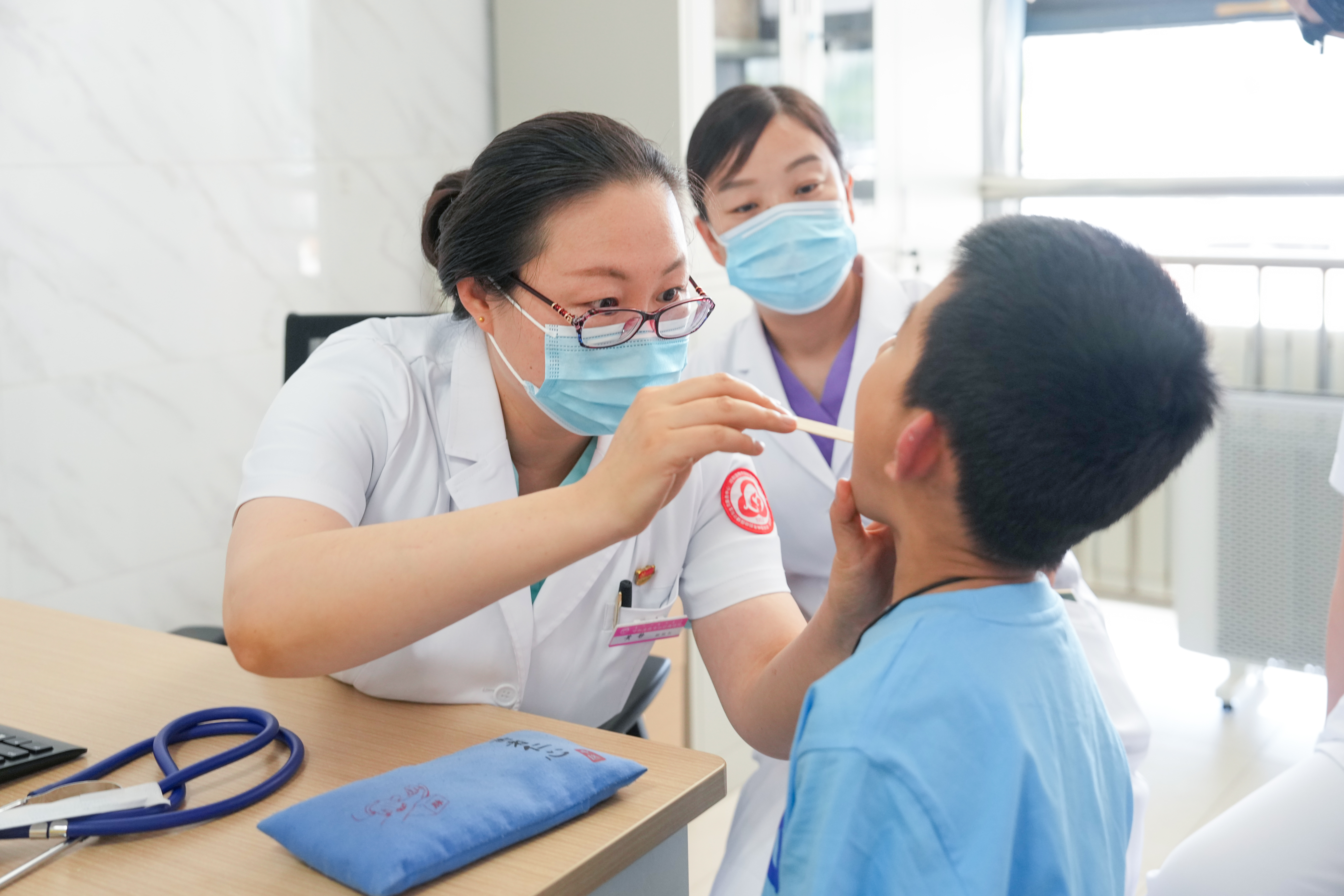 在呼和浩特市妇幼保健院中医儿科门诊，挂职副院长黄静（左一）在细查看患儿咽喉情况。