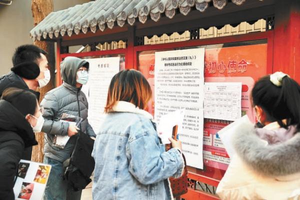 1月8日上午，参加国考的考生入场前认真阅读考试信息。