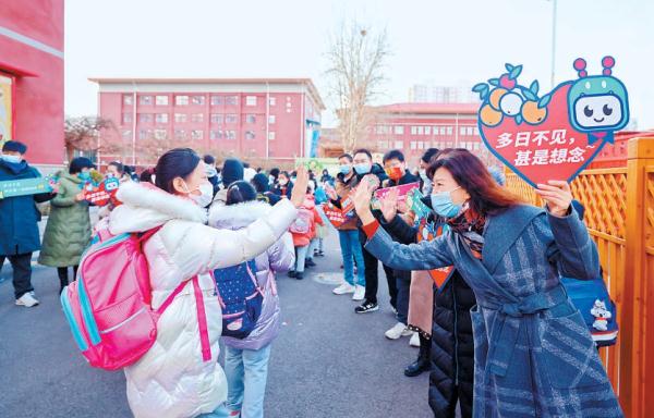 2月13日一早，在北京十一学校一分校，老师们手持欢迎牌，迎接学生返校。