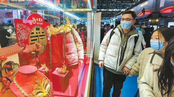 婚博会上，一对情侣欣赏黄金品牌展出的婚庆饰品。
