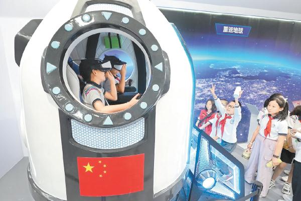 小观众登上“神舟飞船”体验太空遨游。