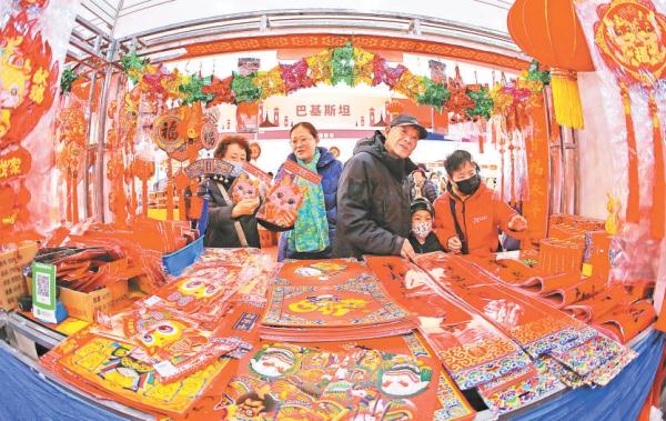 春节的脚步越来越近，不少市民已经开始采买年货。在新工体举办的2024年货博览会上，市民在采购春联等节庆物品。