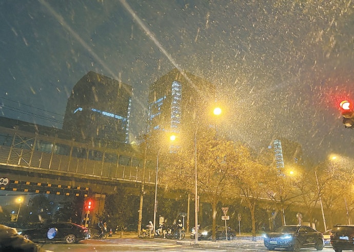 11月26日晚，北京城区迎来降雪。在海淀区荷清路，雪花纷纷扬扬飘落。