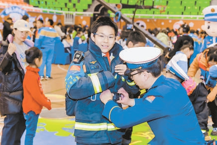 学生在活动现场参与消防战斗服体验活动。