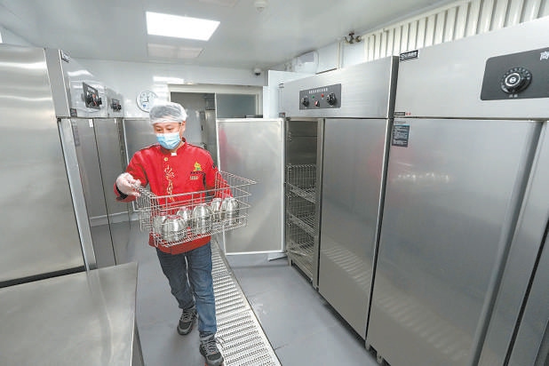校尉胡同小学食堂工作人员使用消毒柜对餐具集中消毒。本报记者和冠欣摄