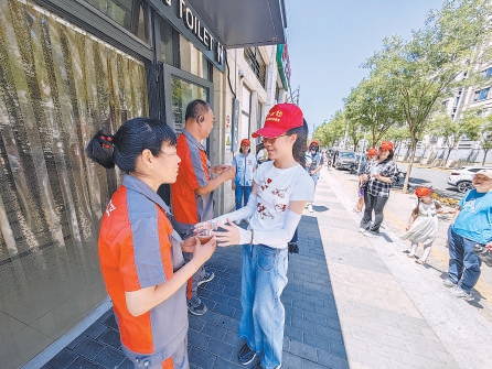 上周末，石景山区古城街道建兴街社区工作人员和志愿者将冰镇好的绿豆汤送到户外工作者手中。