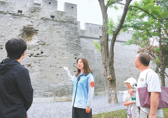 “宛然以平”志愿者向参观者介绍宛平城墙上当年日军进攻留下的弹痕。