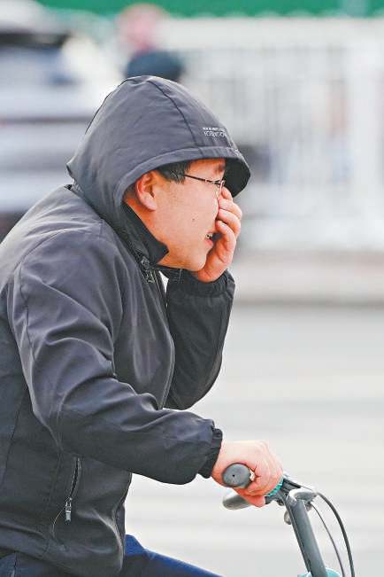 昨天，海淀区五道口，一位市民骑着自行车在风中出行。