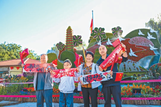 游客在玉渊潭公园西门外“同心奋进 筑梦山河”主题立体花坛前拍照留念。 游客在玉渊潭公园西门外“同心奋进 筑梦山河”主题立体花坛前拍照留念。