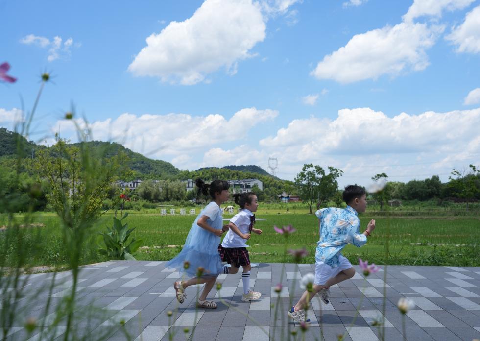 儿童在余姚市梁弄镇的田野间奔跑（7月3日摄）。