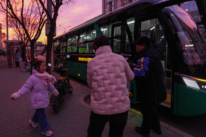12月16日，在北京市朝陽區朝陽路十里堡通學公交站，通學乘務員徐潔（右一）引導一位小學生上車。