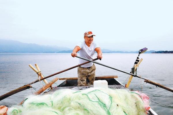 9月25日清晨，“90後”漁民郭小超搖船進入水庫打漁。