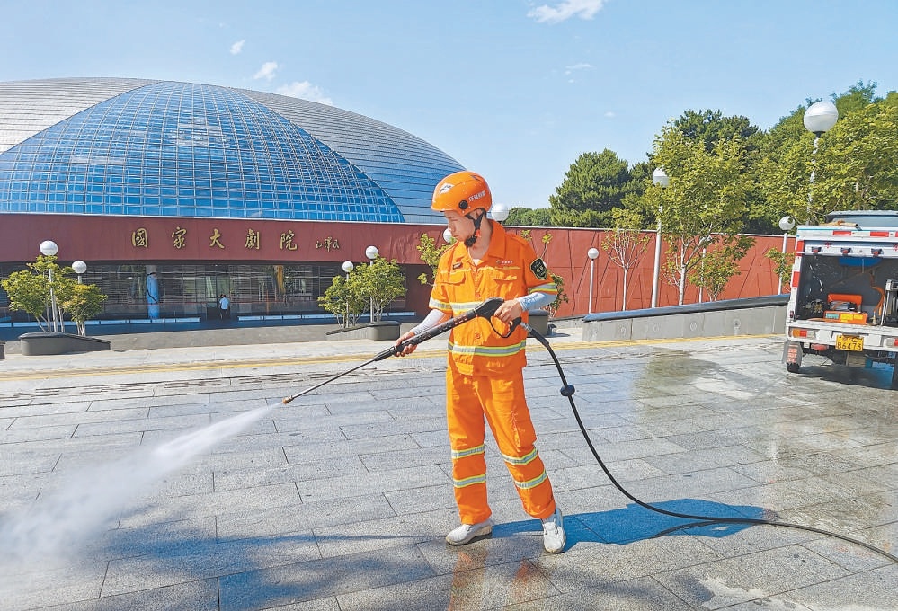 6月12日，在國家大劇院前廣場，環雅麗都（西城環衛）職工在高溫下堅守崗位，進行步道清掃作業。