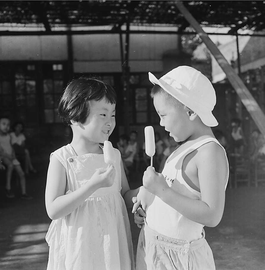 1962年夏，兩個幼兒園小朋友正高興地吃着冰棍。