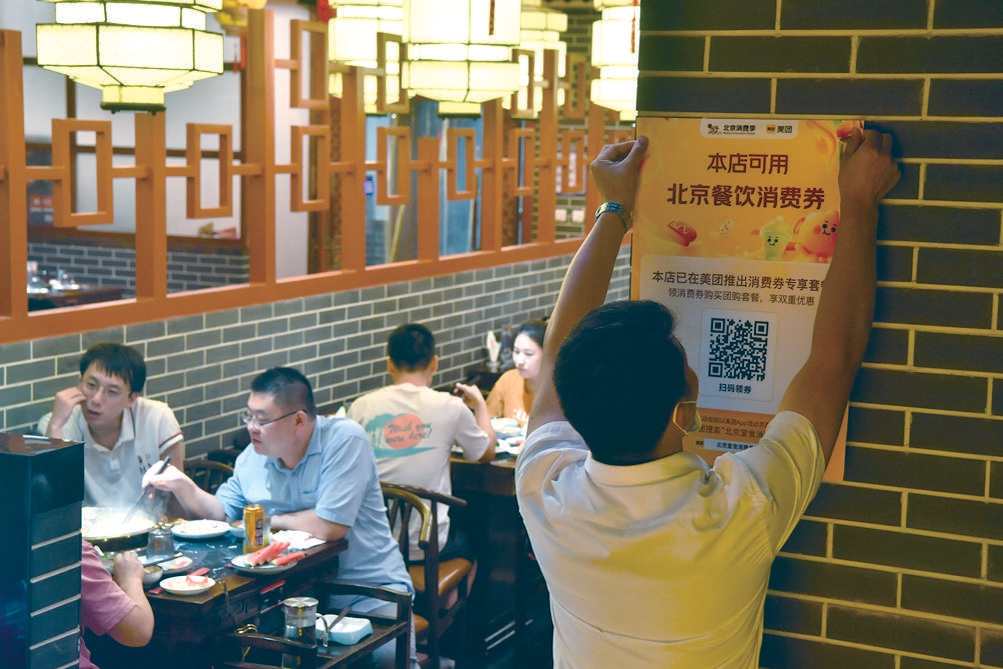 本市發放了餐飲消費券，北京一火鍋店員工在店內貼上宣傳海報。