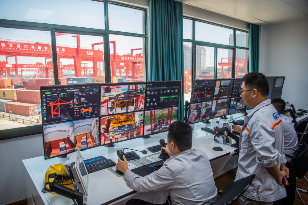工作人員在武漢新港陽邏集裝箱港區遠端操作機械設備吊裝集裝箱（2023年7月5日攝）。
