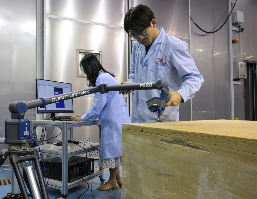 在敦煌研究院多場耦合實驗室中，工作人員正在對慶陽北石窟寺砂岩樣品進行三維掃描分析（2023年8月3日攝）。