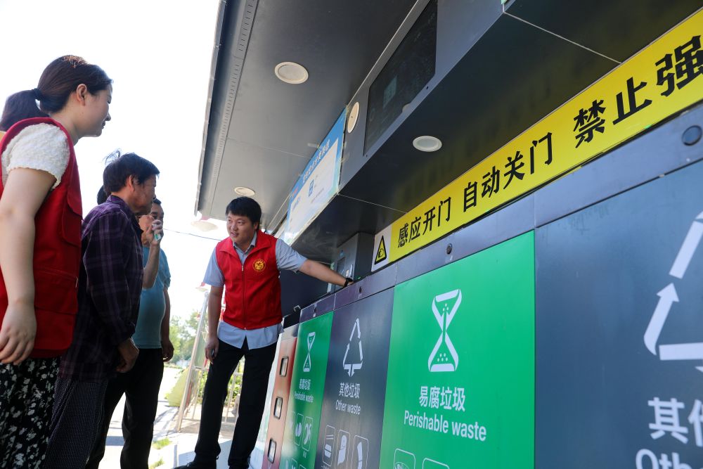 在安徽省合肥市長豐縣莊墓鎮棗林社區，志願者指導居民使用智慧垃圾分類回收設備（2023年9月1日攝）。
