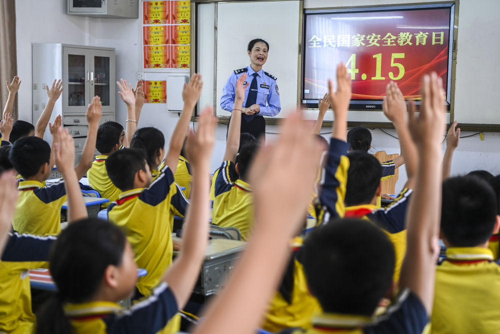 2024年4月15日，在廣西興業縣一所小學內，公安民警在講解國家安全相關知識的過程中與學生們互動。