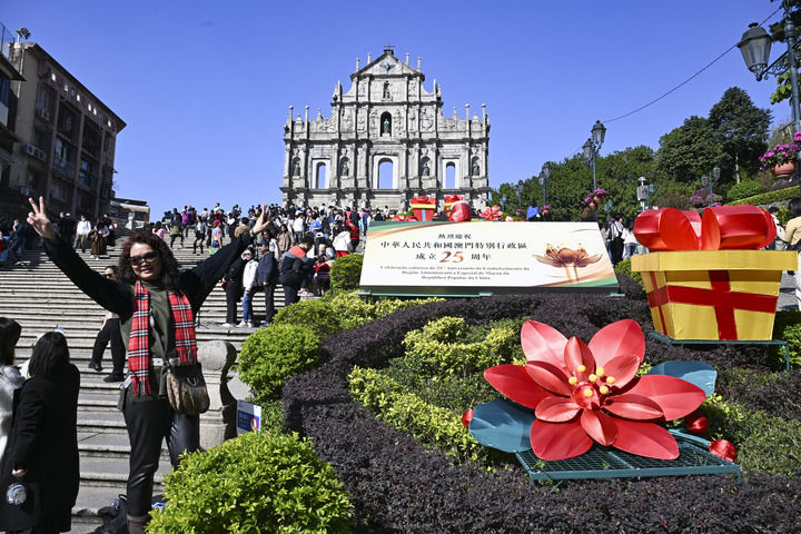 游客在澳門大三巴牌坊慶祝布景旁留影（2024年12月18日攝）。