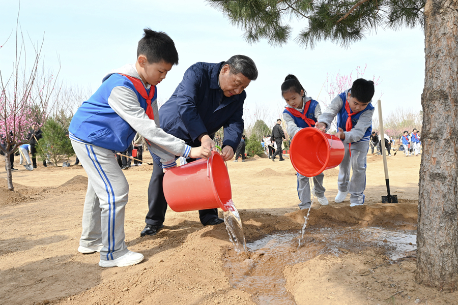 4月3日，黨和國家領導人習近平、李強、趙樂際、王滬寧、蔡奇、丁薛祥、李希、韓正等來到北京市豐台區永定河畔參加首都義務植樹活動。這是習近平同少先隊員一起給剛栽下的樹苗澆水。