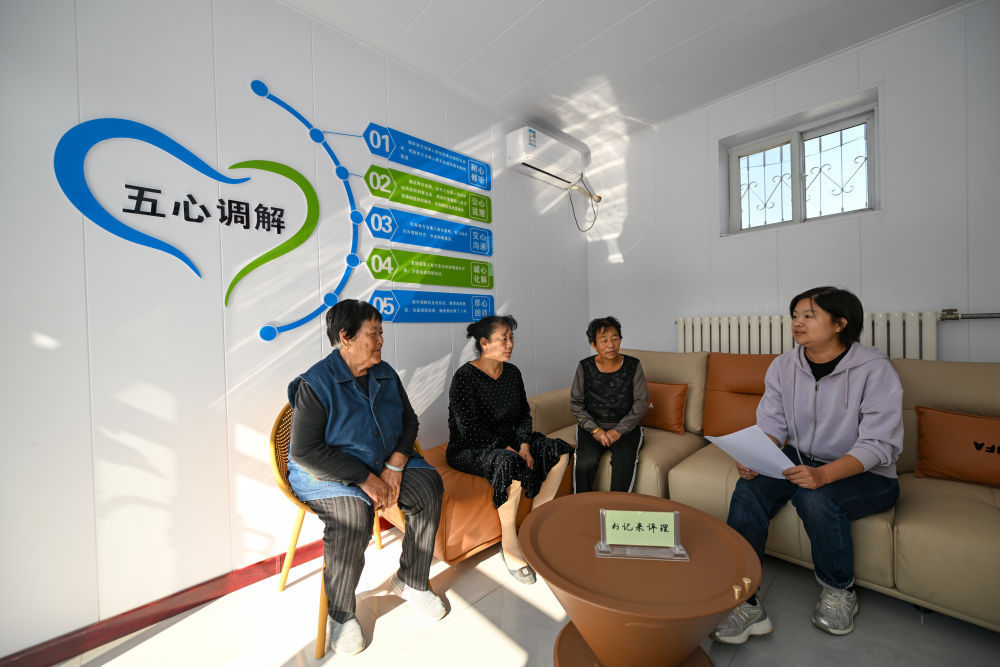 在天津市寧河區蘆臺街道金華路社區，社區黨總支副書記吳蕊（右一）就社區監控設備安裝問題為社區居民進行解答（2024年10月11日攝）。金華路社區積極踐行新時代“楓橋經驗”，將原社區居委會閒置用地提升改造成為聯絡群眾的基層綜合治理陣地——“解鈴小院”。