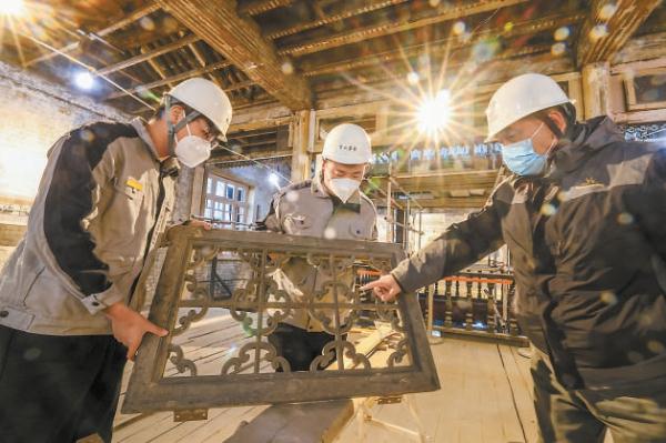 在東城區西曉市街同興和木器店舊址修繕現場，京誠集團老工匠劉京生（右）向年輕學員傳授技藝。