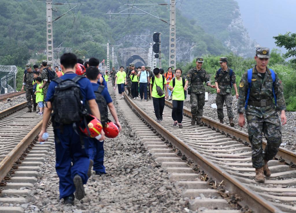 8月2日，部分滯留在北京市門頭溝山區受困列車的旅客，在救援人員幫助下前往轉運客車。