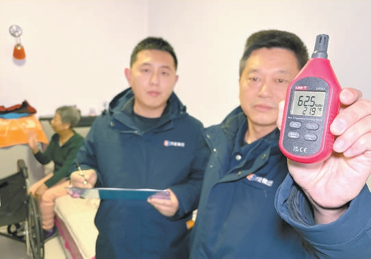 供熱管家段勇（右一）和同事入戶測量，居民家室溫21.9℃達標。
