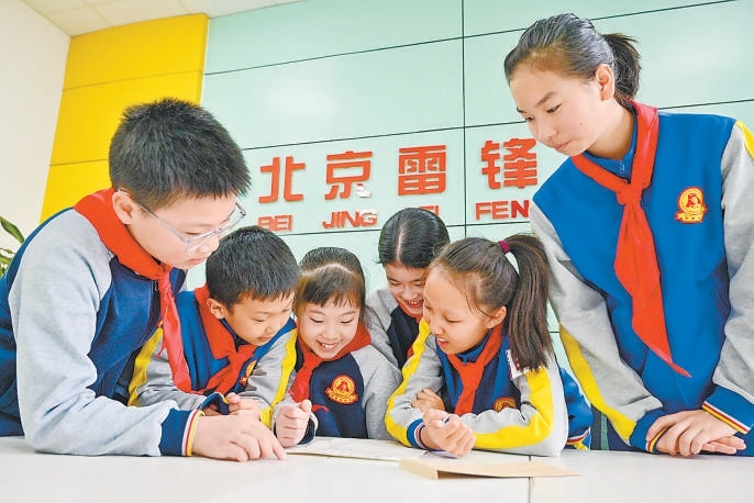 雷鋒小學學生趙悅辰（左三）與同學們閱讀雷鋒班的回信。