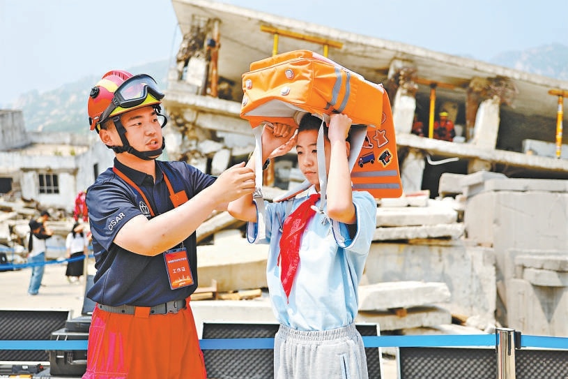 5月12日，國家地震緊急救援訓練基地，工作人員指導學生體驗應急防護書包，學習地震避險中的自我保護技能。