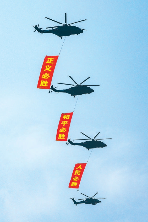 空中護旗梯隊直升機懸挂“正義必勝”“和平必勝”“人民必勝”條幅。
