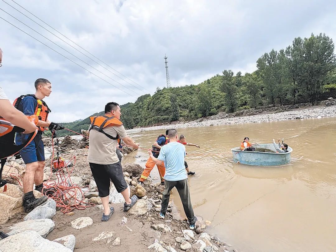 在碾子灣村的一片民宿區，消防救援人員協助遊客渡河。