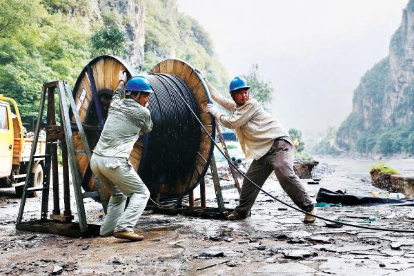 在房山十渡10千伏臥龍路，國網北京電力密雲電力保通隊進行放纜架線工作，期間陣雨來襲，他們的工作始終不曾停歇。