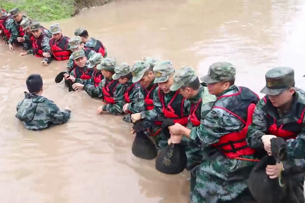 8月2日，中部戰區空軍某部官兵在北京市昌平區北沙河鎮南側搭設人墻並裝填沙袋。