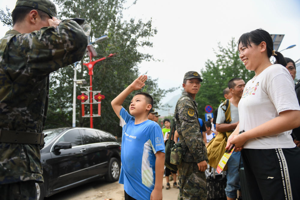 8月2日，在北京市門頭溝區妙峰山鎮，在乘坐車輛轉移前，自內蒙古的三年級小學生武天騏（中）向武警北京總隊機動第三支隊的王雷鳴敬禮感謝。