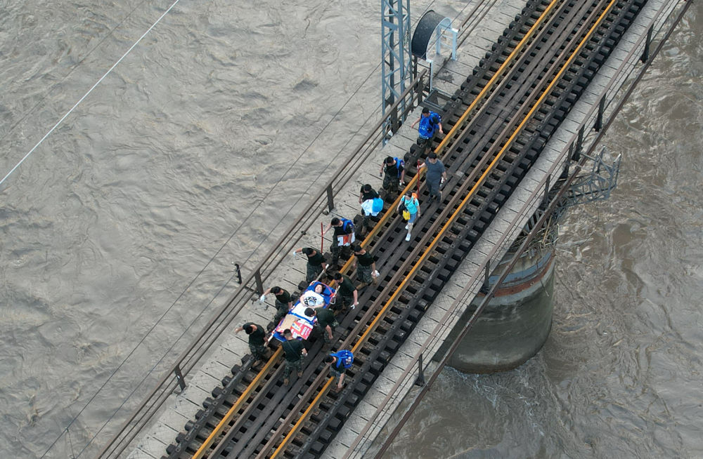 8月2日，受困列車旅客在救援人員幫助下徒步趕往轉運客車（無人機照片）。