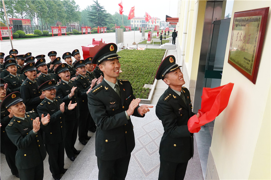 陸軍第83集團軍某旅“紅一連”官兵在連隊門前懸挂“星火燎原”育人基地牌匾