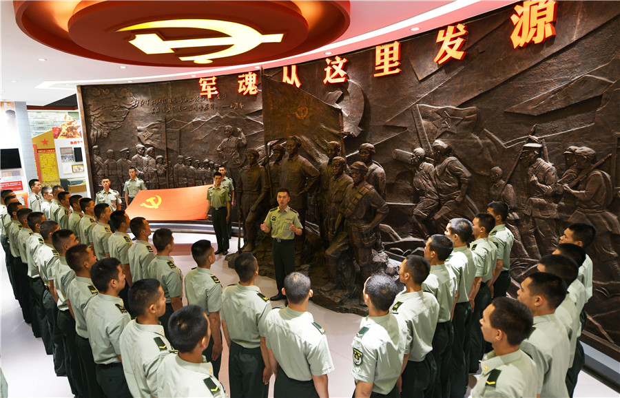 在陸軍第83集團軍某旅“紅一連”連史館“軍魂從這裡發源”雕塑前，指導員鄭紀文(中)為官兵講述“支部建在連上”的光榮歷史