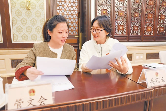 3月10日，十四届全国人大三次会议北京市代表团召开全体会议，审议全国人大常委会工作报告和“两高”工作报告。图为两位代表在讨论交流。